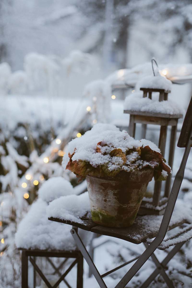 ice cream planter and lantern covered with snow outdoor cream